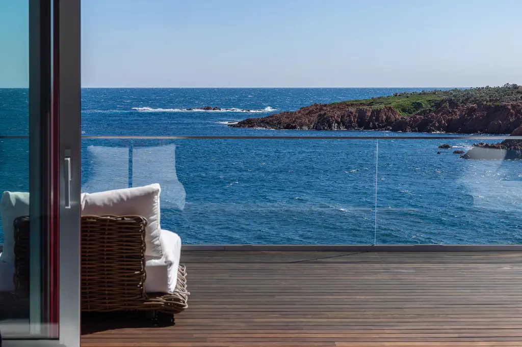 La terrasse en bois derrière la baie vitrée, face à la mer