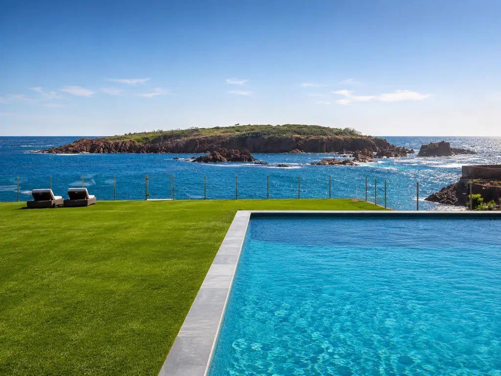 La piscine et la pelouse face à l’îlot de roches rouges