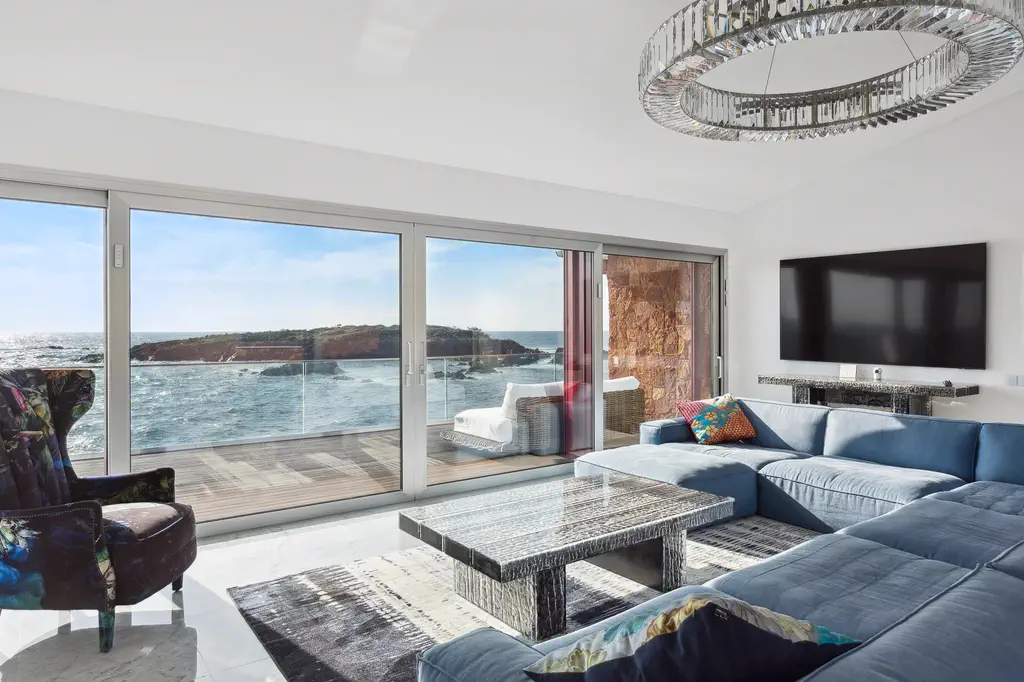 Le séjour lumineux, canapés et lustre, face à la mer