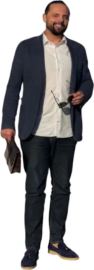 Homme en gilet bleu nuit et chemise blanche, lunettes de soleil à la main